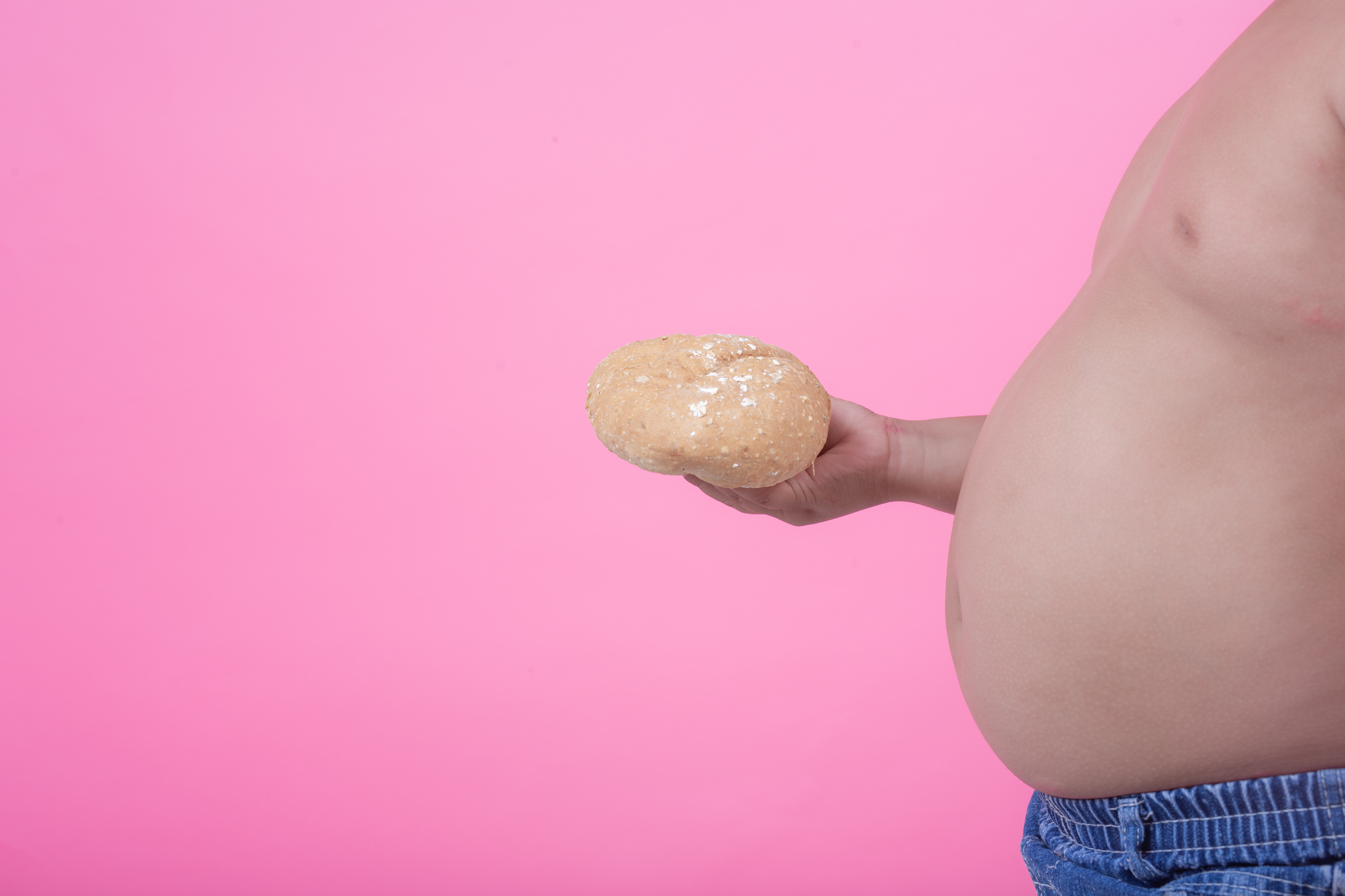 Obese boy who is overweight on a pink background.